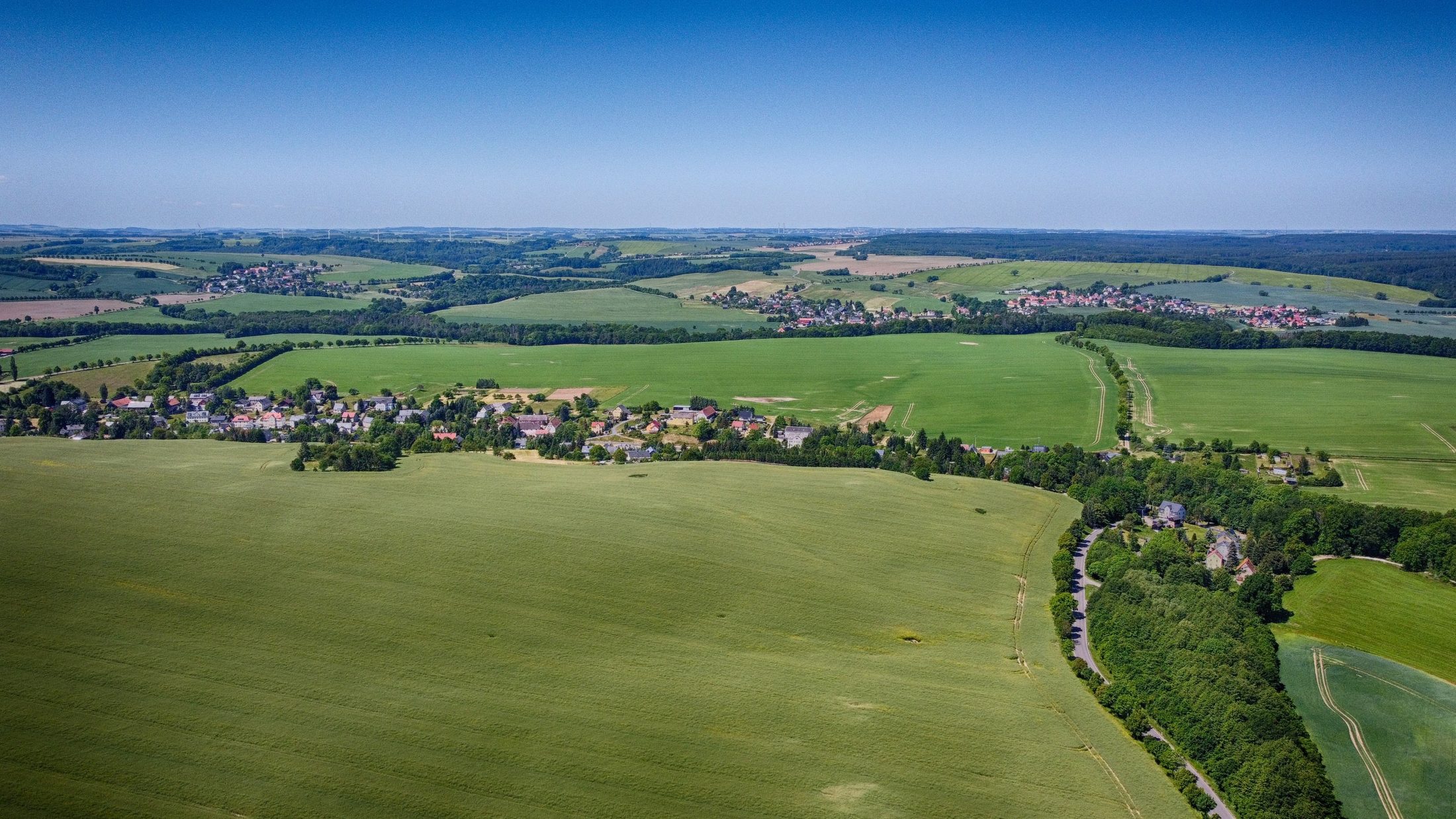 Weite gruene Felder und Doerfer der saechsischen Landschaft aus der Luft