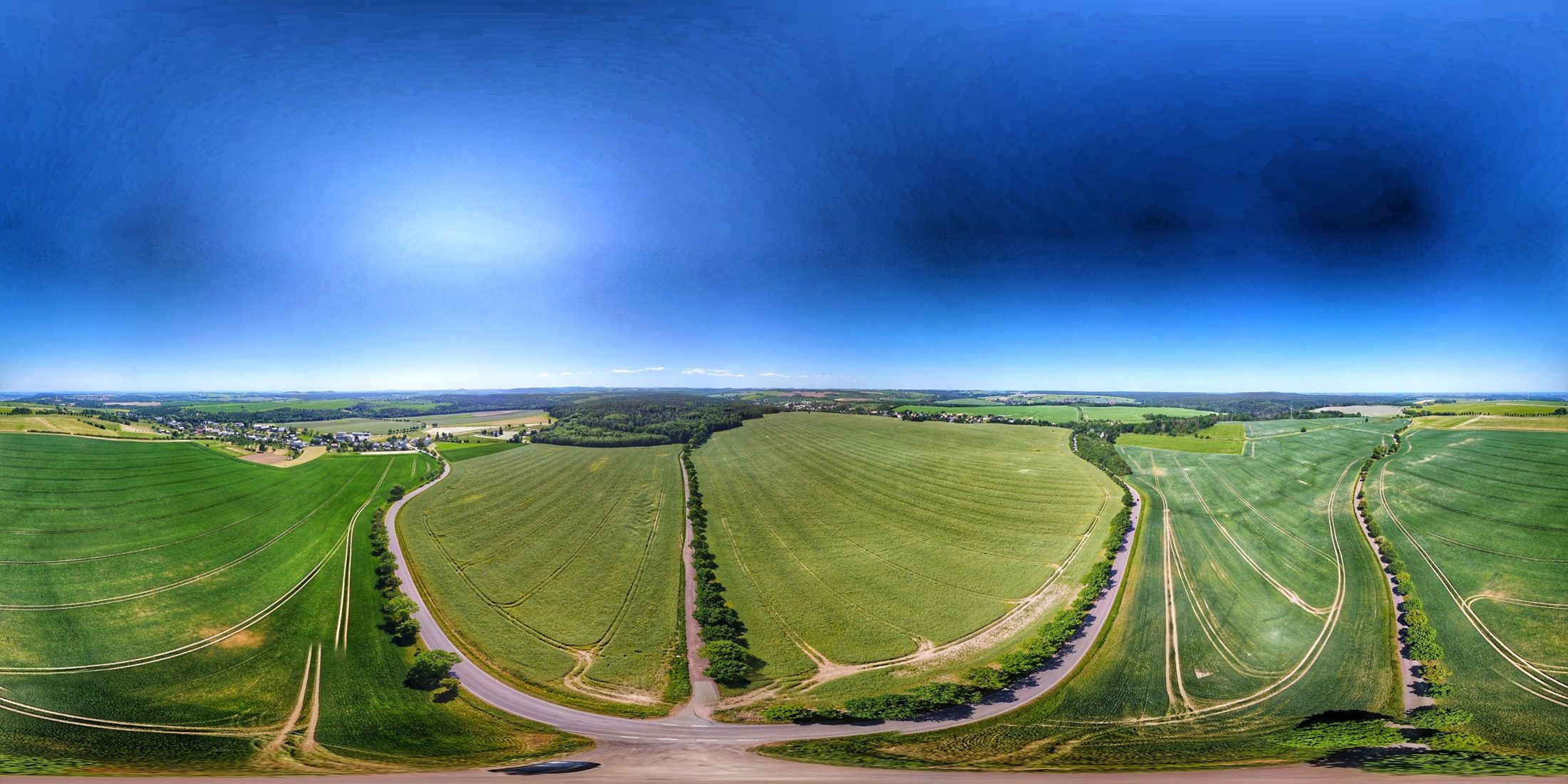 360°-Drohnenpanorama ueber Feldern, Feldwegen und Doerfern unter blauem Himmel